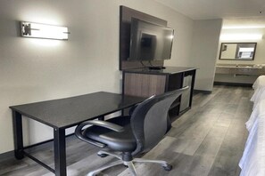 A hotel room with a desk, chair, TV, and a bed. - Griffin Inn & Suites (Griffin)