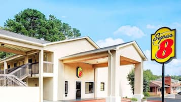 A motel with a Super 8 sign, a covered parking area, and a two-story structure with a balcony.
