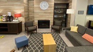 A modern living room with a fireplace, seating area, and a clock on the wall. - Comfort Inn & Suites Fairburn - Atlanta Southwest (Fairburn)