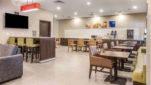 A modern restaurant with a bar area, multiple dining tables, and a kitchen in the background. - Comfort Inn & Suites Fairburn - Atlanta Southwest (Fairburn)