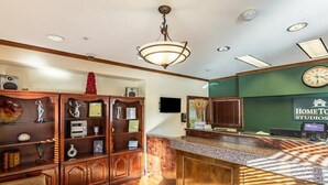 A reception area with a wooden reception desk, a clock, and a sign for 'Home to Studios'. - Hometowne Studios Atlanta - Chamblee (Chamblee)