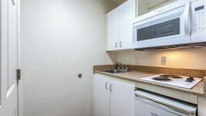 A kitchen with white cabinets, a microwave, a stove, and a dishwasher. - Hometowne Studios Atlanta - Chamblee (Chamblee)
