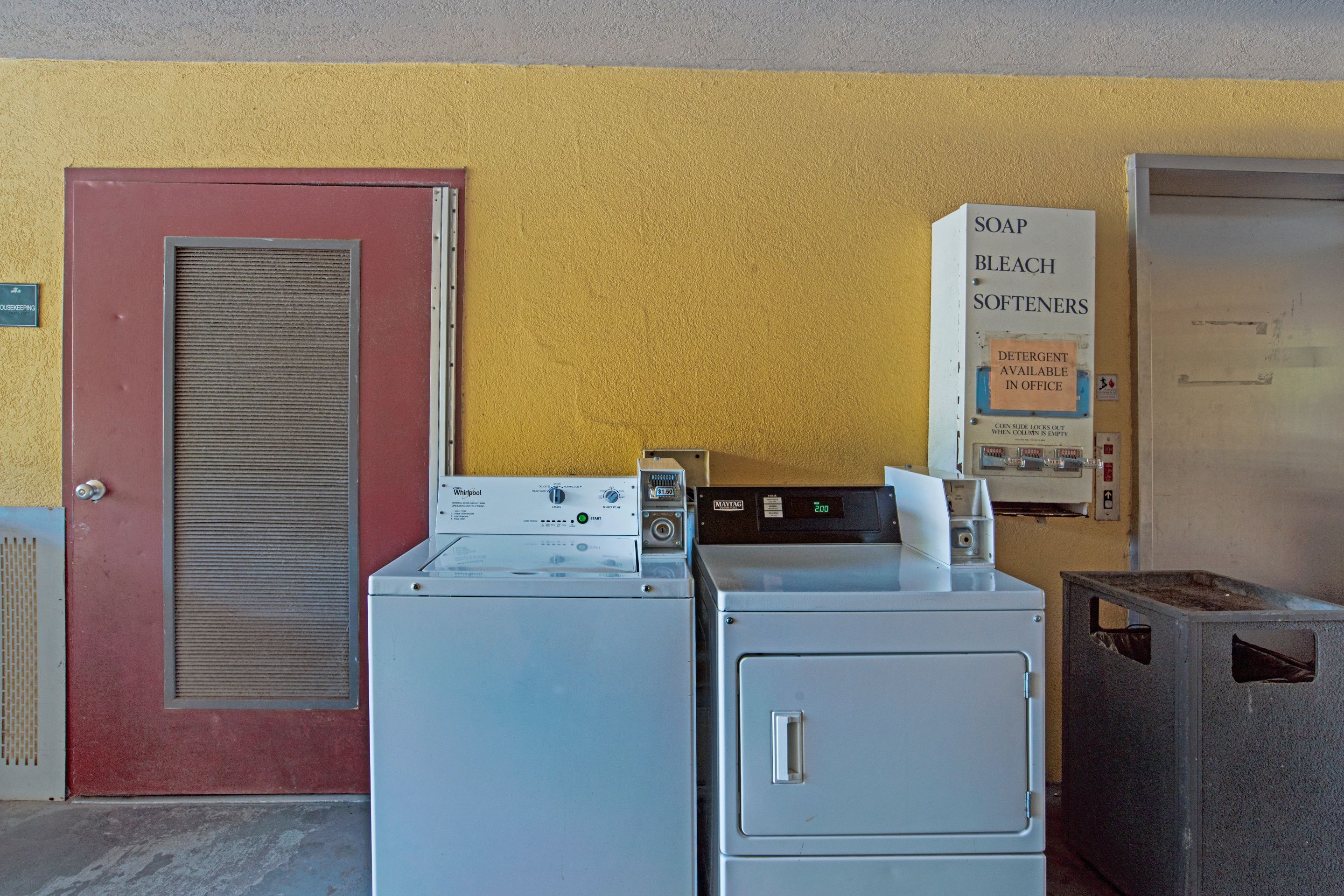 A laundry facility with washers and dryers, a detergent dispenser, and a sign indicating soap, bleach, and softeners are available.