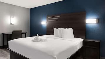 A hotel room with a large bed, bedside tables, a desk, and wall-mounted lights.