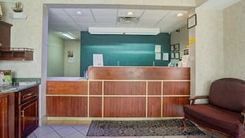 A reception area with a wooden reception desk, a dark patterned rug, and a brown chair.