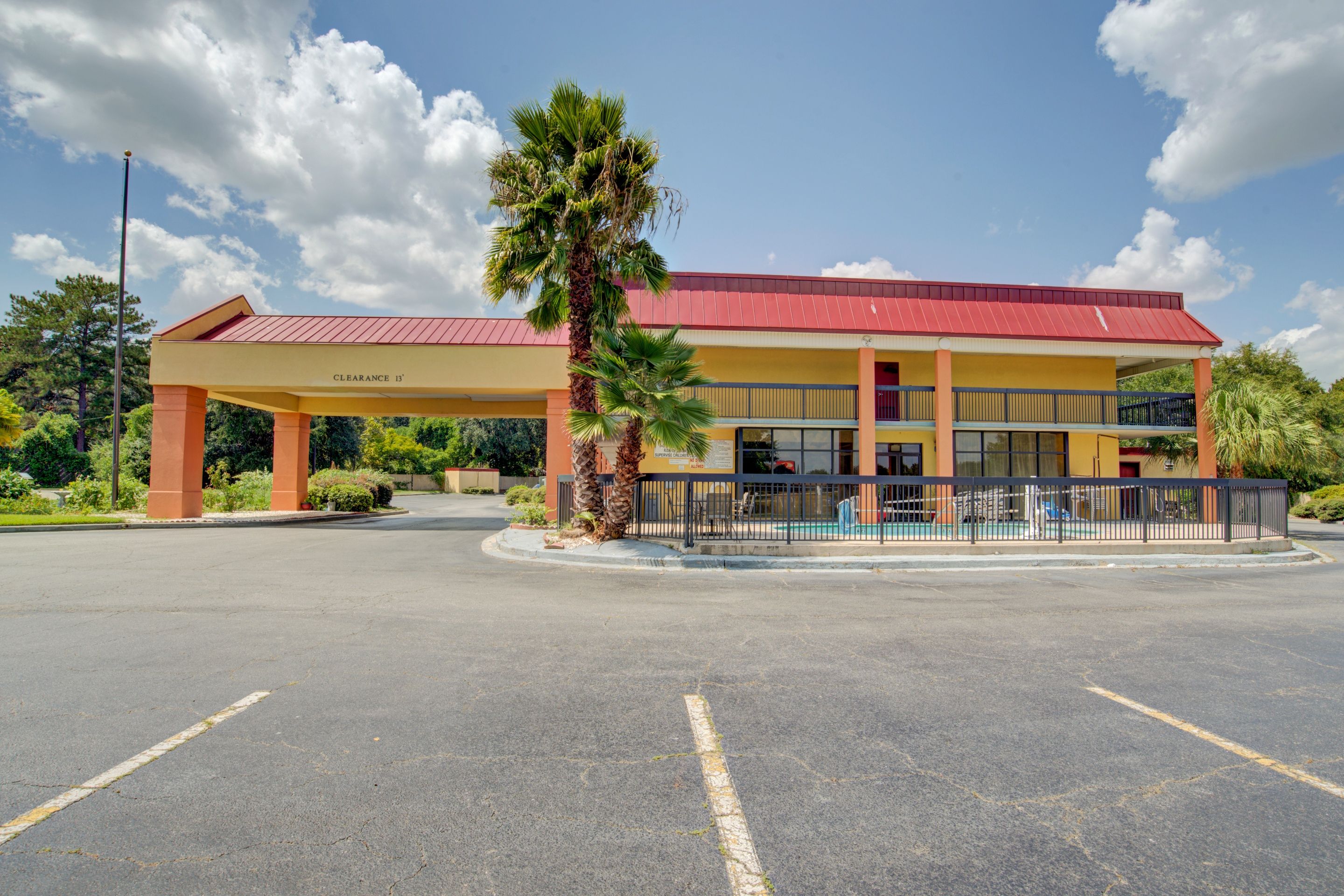 A building with a red roof, yellow walls, and a covered parking area.