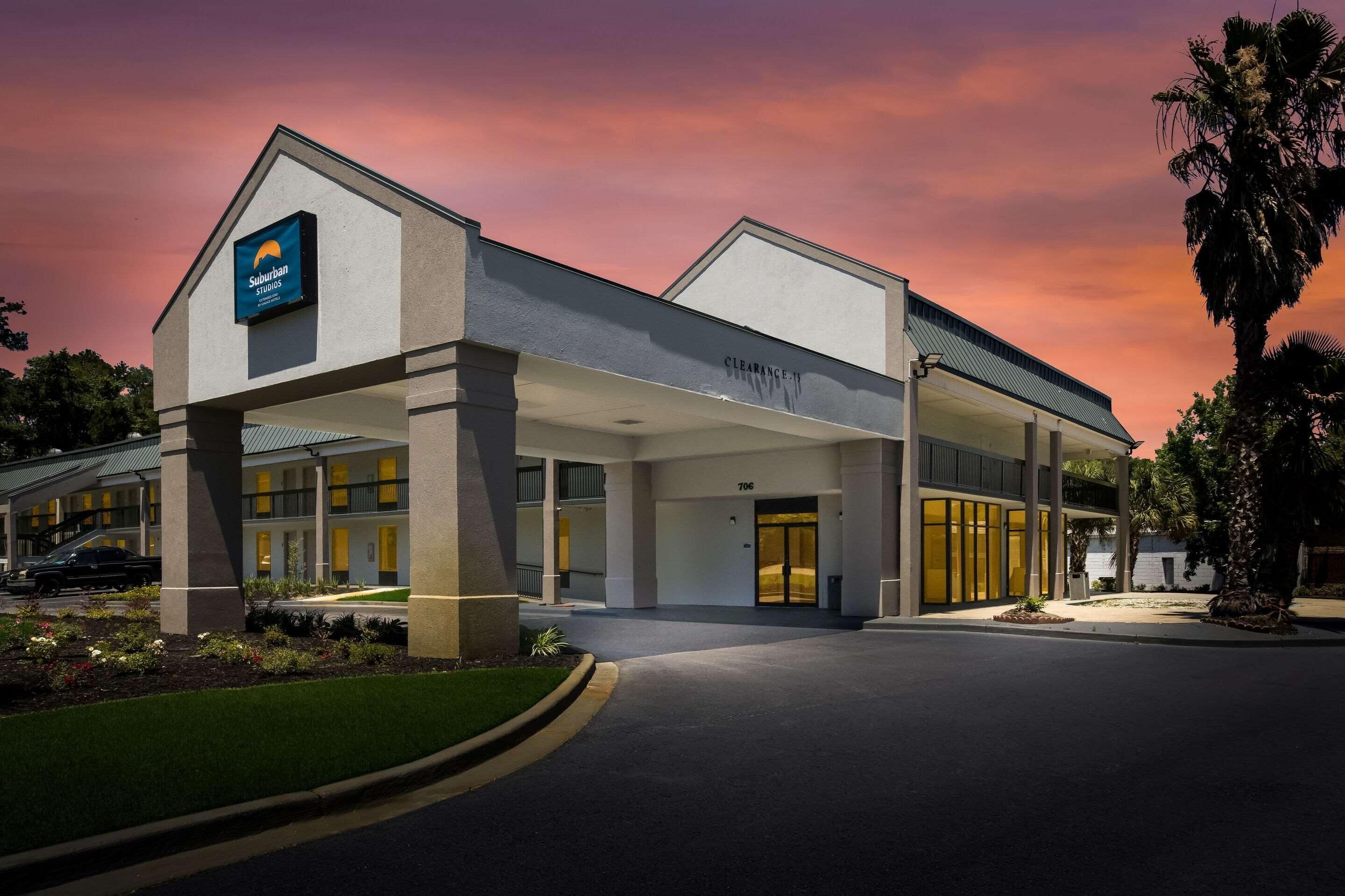 A hotel with a clear entrance, a sign for 'Suburban Studios,' and a 'Clearance' sign.
