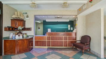 Ein Empfangsbereich mit einem Holztisch, einer Rezeptionstheke, einem dekorativen Schiffsmodell und einem Vintage-Sessel.