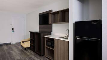 A compact kitchen with a microwave, a refrigerator, and wooden cabinets.