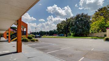 A parking lot with a covered walkway, trees, and a clear sky.