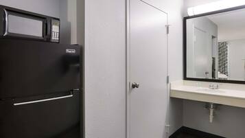 Ein kleines Badezimmer mit Kühlschrank, Waschbecken und Spiegel.