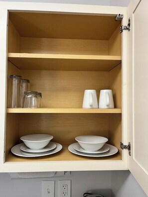 Un armario de cocina con tres estantes, cada uno con diferentes utensilios de cocina.