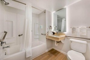 Un baño con bañera, inodoro, lavabo y espejo.