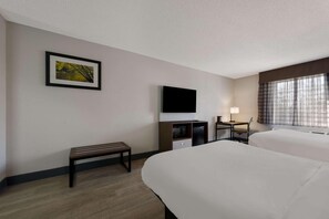 A hotel room with two beds, a desk, a chair, a television, a bench, and a framed picture on the wall. - Quality Inn University Area Farmville, VA (Farmville)
