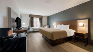 Een hotelkamer met een groot bed, nachtlampjes, een bureau met een computer en een televisie.