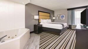 A hotel room with a large bed, a separate bathroom with a bathtub, a desk with a computer, and a window with curtains. - OYO Townhouse Jackson/ridgeland (Jackson)