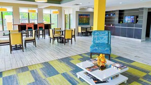 A hotel lobby with a dining area, a TV, and a statue on a coffee table. - OYO Townhouse Jackson/ridgeland (Jackson)