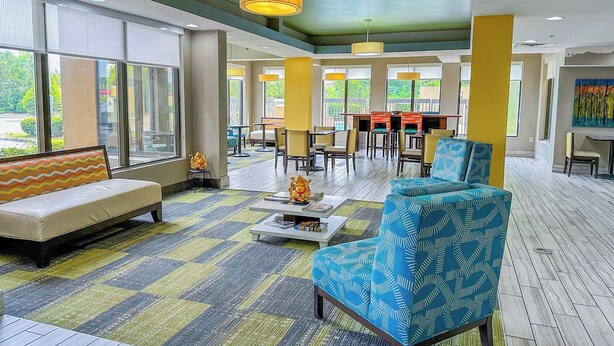 A spacious lobby with a sofa, armchair, coffee table, and dining area. - OYO Townhouse Jackson/ridgeland (Jackson)