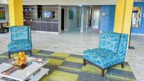 A lobby with two patterned armchairs, a reception desk, and a coffee table with magazines. - OYO Townhouse Jackson/ridgeland (Jackson)