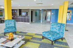 Un vestíbulo con dos sillones estampados, una mesa de recepción y una mesa baja con revistas.
