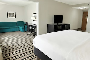 A hotel room with a bed, a sofa, a desk, and a television. - OYO Townhouse Jackson/ridgeland (Jackson)