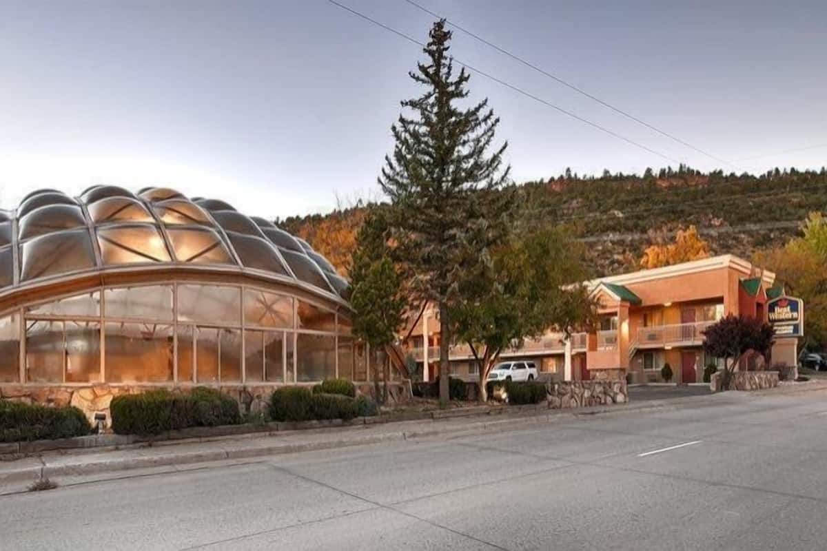A modern building with a unique dome structure, a parking area, and a sign for a hotel.