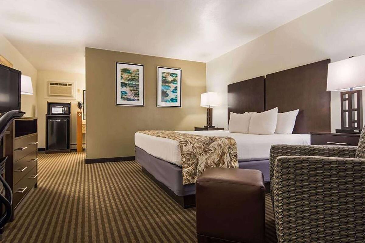 A hotel room with a bed, a desk, a chair, a television, and two framed pictures on the wall.