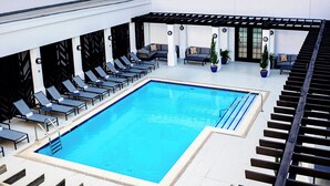 Une piscine sur le toit, agrémentée de chaises longues, d’une pergola et de plantes en pot.