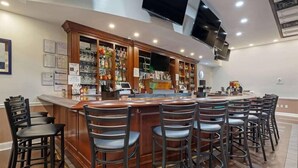 A bar area with a long counter, multiple stools, and a variety of bottles and glasses on shelves. - Clarion Hotel & Suites BWI Airport North (Baltimore)