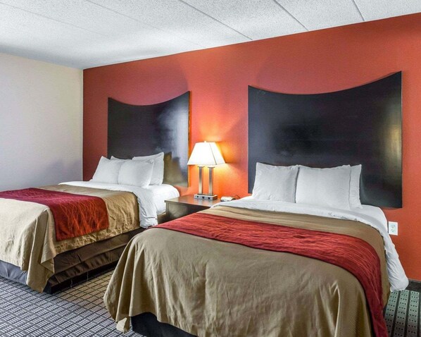 A hotel room with two beds, a red and beige color scheme, and a nightstand with a lamp. - Clarion Hotel & Suites BWI Airport North (Baltimore)