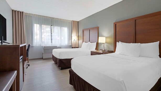 A hotel room with two beds, a desk, and a TV. - Clarion Hotel & Suites BWI Airport North (Baltimore)