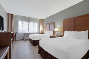 A hotel room with two beds, a desk, and a TV. - Clarion Hotel & Suites BWI Airport North (Baltimore)