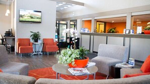 A modern lobby with seating areas, a reception desk, and a television mounted on the wall. - Colony Inn Hotel Atascadero (Atascadero)