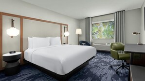 A hotel room with a large bed, a desk, a chair, and a window with curtains. - Colony Inn Hotel Atascadero (Atascadero)