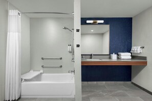 A modern bathroom with a bathtub, shower, and vanity with a mirror. - Colony Inn Hotel Atascadero (Atascadero)
