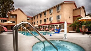 A hotel pool area with a pool, lounge chairs, and umbrellas. - Colony Inn Hotel Atascadero (Atascadero)
