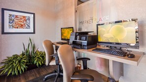 A modern office space with two desks, each equipped with a computer monitor, keyboard, and mouse. There are two office chairs, and the room features a framed artwork on the wall. - Colony Inn Hotel Atascadero (Atascadero)
