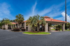 A hotel with a red-tiled roof, palm trees, and a parking lot. - Super 8 By Wyndham Savannah (Savannah)
