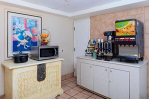 A kitchenette with a microwave, coffee machine, and juice dispenser. - Super 8 By Wyndham Savannah (Savannah)