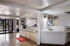 A hotel reception area with a reception desk, a digital clock, and a sign for 'EconoLodge.' - Super 8 By Wyndham Savannah (Savannah)