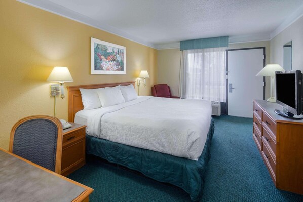A hotel room with a bed, two bedside lamps, a TV, a desk, and a chair. - Super 8 By Wyndham Savannah (Savannah)