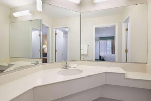 Un baño moderno con un espejo grande, un lavabo y una zona de ducha.