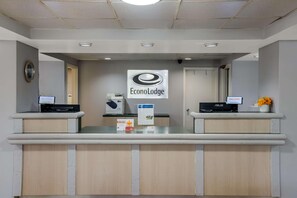 A reception desk with a sign reading 'EconoLodge,' a clock, and a computer monitor. - Super 8 By Wyndham Savannah (Savannah)