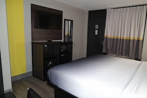 A hotel room with a bed, a TV mounted on the wall, a wardrobe, and a door with a curtain. - Super 8 By Wyndham Savannah (Savannah)