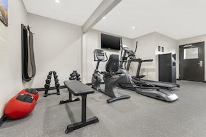 Un gimnasio con equipo de ejercicio, una banca y una cinta de correr.