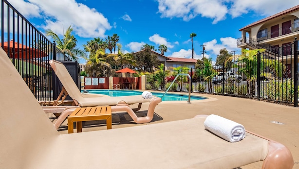 A pool area with lounge chairs, a pool, and a fenced garden. - Best Western San Diego Pacific Beach/mission Bay (San Diego)