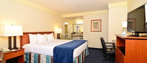 A hotel room with a bed, desk, chair, and a television.