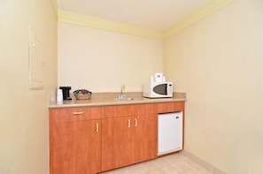 Una kitchenette con armarios de madera, un microondas, un lavabo y un refrigerador pequeño.