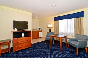 A hotel room with a television, a desk, a chair, a small table, a sofa, a minibar, and a window with curtains. - Best Western San Diego Pacific Beach/mission Bay (San Diego)