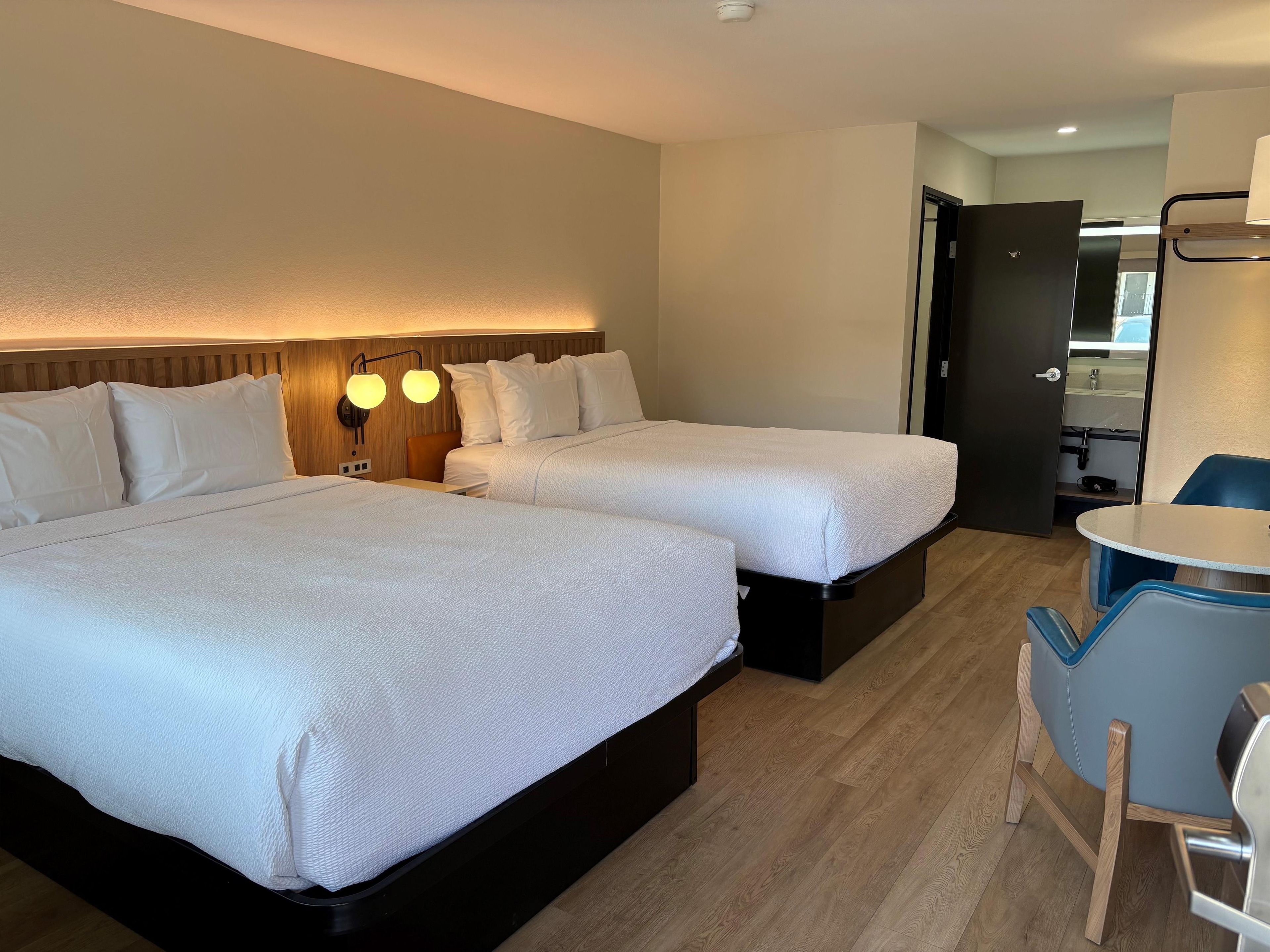 A hotel room with two beds, a desk, and a chair.